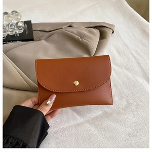 Detail of a brown woven PU leather envelope bag featuring a gold metal snap closure