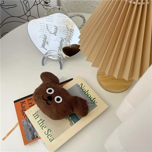 Detail of cute brown plush bear charm with metal chain on a minimalist white desk