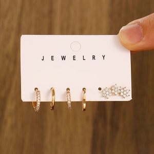 Macro shot of 5-piece gold piercing earring set with zircon flowers on a jewelry card