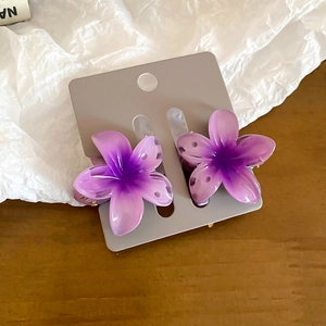 Detailed close-up of a pair of purple gradient resin flower hair clips on display card