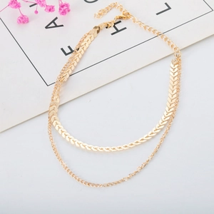 Detail of double-layer gold snake chain necklace with arrow pendant and round beads