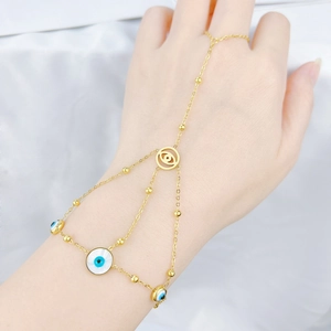 Gold evil eye hand chain ring bracelet set with blue eye charms on white satin background