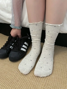 Detail view of beige polka dot mid-tube socks with elegant ruffle cuffs and cotton texture