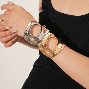 Gros plan d'un large bracelet manchette géométrique évidé en métal sur un poignet