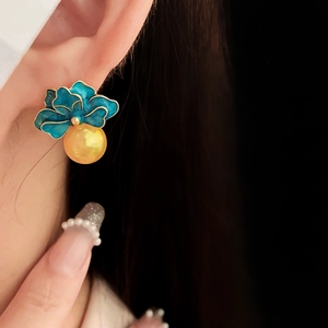 Detailed close-up of vintage blue enamel flower earrings with gold pearls on a model