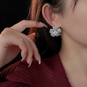 Detail shot of sparkling silver flower stud earring with cubic zirconia on a model
