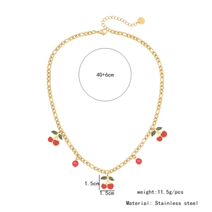 Détail du collier doré en acier inoxydable avec pendentifs cerises et perles rouges sur chaîne