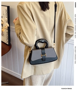 Detail of grey fabric and black leather contrast handbag with elegant gold metal buckle