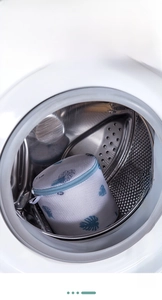 Detailed view of leaf pattern mesh laundry bag for bras inside a washing machine drum