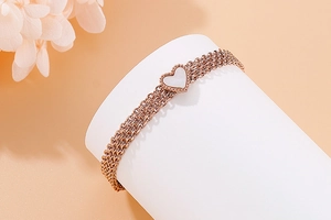 Detail of rose gold multi-strand bracelet with heart pendant on floral display