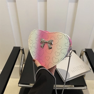 Rainbow gradient heart-shaped crossbody bag with a metallic bow and gold chain strap