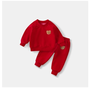 Detail of red kids tracksuit with cozy fleece lining and cute brown teddy bear patches