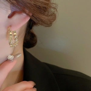 Macro view of gold U-shaped zircon earrings with sparkling textured finish on ear