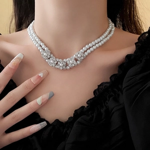 Double-layered pearl necklace with diamond flower accents on a model in elegant side view
