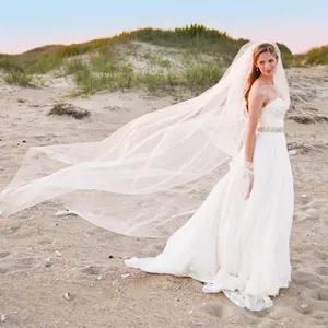 Elegant long single-layer white bridal tulle veil flowing in the wind at the beach