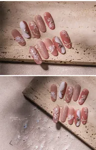 Detail of nude pink nails with 3D white flower relief, tiny pearls and fine glitter texture