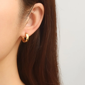 Créoles dorées chic avec facettes géométriques portées par un mannequin pour un look de luxe