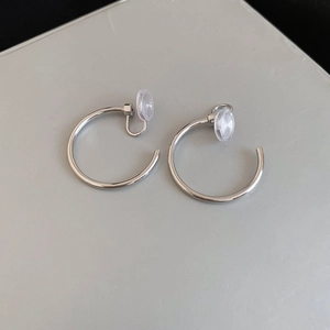 Detailed macro view of silver C-shaped clip-on earrings with clear silicone pads