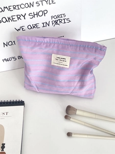 Detail of purple striped canvas makeup bag with soft cotton texture and woven label