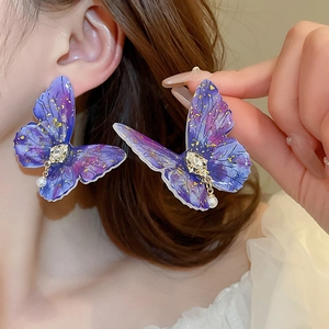 Macro view of large gradient purple butterfly earring with crystals and a pearl drop