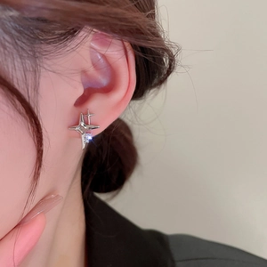 Elegant silver four-point star earrings with zircon stone worn by a model in a close-up