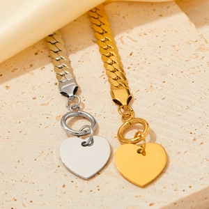Detail of gold and silver snake chain bracelets with heart charms and OT toggle clasps