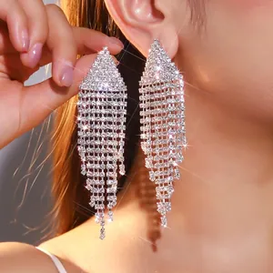 Close-up of elegant silver long tassel rhinestone earrings worn by a model
