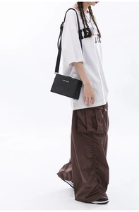 Close-up of a black rectangular crossbody bag with adjustable strap and brand logo