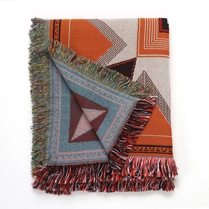Close-up of geometric woven blanket with bohemian colorful tassels and textured fabric