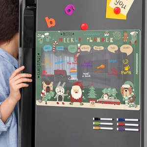 Close-up of magnetic acrylic weekly planner on fridge with Christmas theme and markers