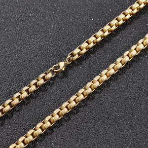 Golden stainless steel box chain necklace with lobster clasp on a black background