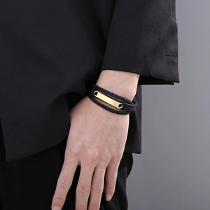 Close-up of a multi-layer black braided leather bracelet with a polished gold metal plate