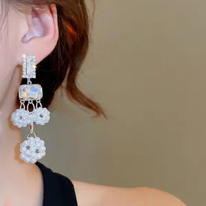 Elegant silver tassel earrings with crystal hollow spheres and white beads on a model