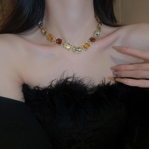 Detail of vintage gold necklace with amber and yellow square rhinestones on a model