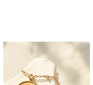 Macro shot of gold-plated stainless steel necklace with textured round pendant detail