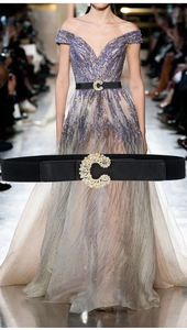 Close-up of elegant C-shaped rhinestone buckle on a black elastic leather belt