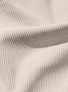 Detailed macro view of beige corduroy fabric texture and soft vertical ribbed patterns