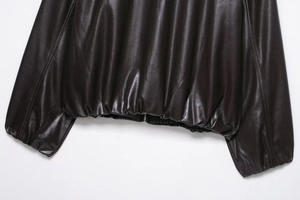 Macro detail of dark brown faux leather jacket hem featuring a metal zipper and elastic cuff