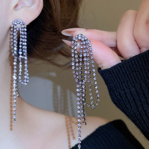 Macro detail of elegant silver needle drop earrings with layered purple crystal tassels