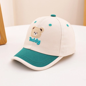 Close-up of beige cotton cap with green brim featuring detailed Teddy bear embroidery