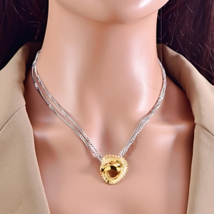 Macro detail of mixed metal double chain necklace with textured gold pendant