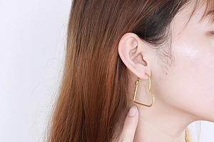 Close-up of heart-shaped gold earrings in stainless steel worn by a model
