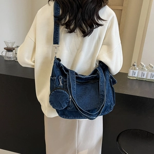 Deep blue denim tote bag with round coin purse and multiple pockets on a female model