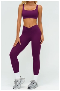 Detail showing high-waisted yoga leggings with V-shaped pleated waist in deep purple color