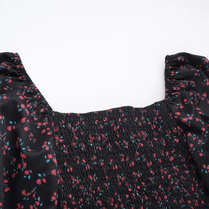 Dettaglio dello scollo quadrato con punto smock e stampa floreale rossa su nero