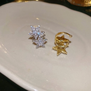 Macro shot of star-shaped ear cuffs in silver with zircons and polished gold finish
