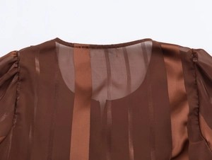 Détail d'une blouse bohème marron avec rayures satinées verticales et encolure crochet