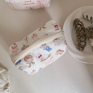 Close-up of a white quilted cotton makeup bag with cute cartoon animal illustrations