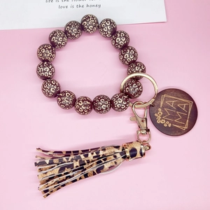 Détail du porte-clés bracelet en perles de bois léopard avec breloque MAMA et pompon en PU
