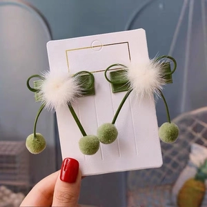 Detailed view of handmade green cherry hair clips with satin bows on a princess display card